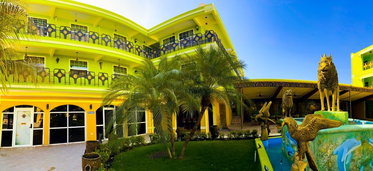 Piscine et façade vert lime de Kingdom Hôtel Haïti, gardée par les statues du lion